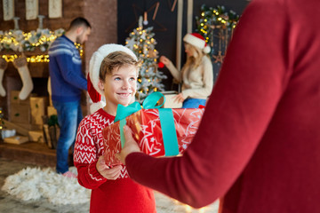 A boy accepts a gift in a room on Christmas day.