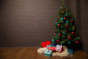 Christmas tree with toys on a background of a brick wall and gifts