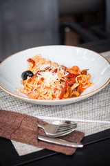 Pasta, spaghetti with herbs, tomatoes and sauce in white bowl