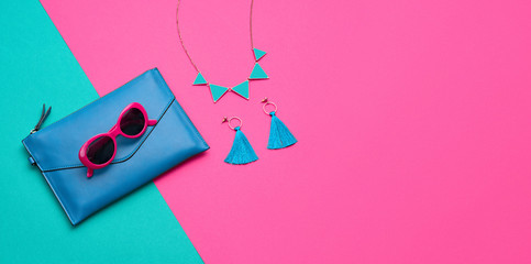 Fashion party girl layout Flat lay. Minimal. Woman Essentials accessories. Trendy Clutch, sunglasses, earrings. Coloful purple green Set. Creative pop art concept, vibrant fashionable color. Banner