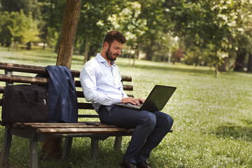 Businessman using laptop sitting on bench