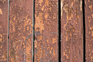 Wooden vertical boards covered with peeling red paint. Beautiful vintage wood texture