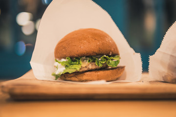 chicken burger on a wooden plate in a cafe