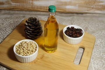 cedar oil in bottle , cone, nuts on wooden background in the kitchen 