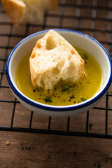 Freshly baked white bread with olive oil and herbs on wooden background.