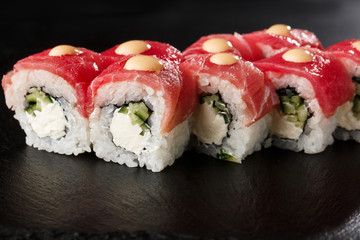 Sushi Rolls with cucumber, tuna, and Cream Cheese inside on black slate isolated. Philadelphia roll sushi with shrimp. Sushi menu. Horizontal photo.