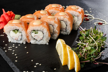 Sushi Rolls with cucumber, shrimp, salmon and Cream Cheese inside on black slate isolated. Philadelphia roll sushi with shrimp. Sushi menu. Horizontal photo.