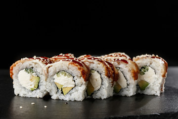 Sushi Rolls with cucumber, avocado, eel and Cream Cheese inside on black slate isolated. Philadelphia unagi roll sushi with shrimp. Sushi menu. Horizontal photo.