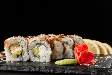 Sushi Rolls with cucumber, avocado, eel and Cream Cheese inside on black slate isolated. Philadelphia unagi roll sushi with shrimp. Sushi menu. Horizontal photo.