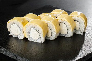 Sushi Rolls with processed cheese, cheddar, american cheese and Cream Cheese inside on black slate isolated. Philadelphia roll sushi with shrimp. Sushi menu. Horizontal photo.