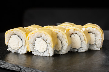 Sushi Rolls with processed cheese, cheddar, american cheese and Cream Cheese inside on black slate isolated. Philadelphia roll sushi with shrimp. Sushi menu. Horizontal photo.