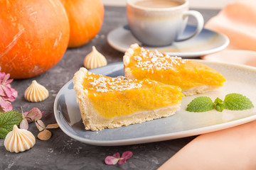 Two pieces of traditional american pumpkin pie with cup of coffee on a black concrete background. side view, selective focus.