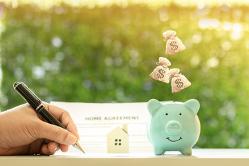 Businessman writing or signing on document business agreement contract and home model for family...