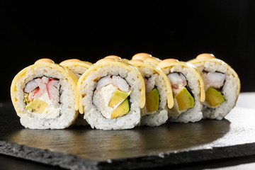 Sushi Rolls with processed cheese, cheddar, american cheese, avocado, crab meat, shrimp and Cream Cheese inside on black slate isolated. Philadelphia roll sushi with shrimp. Sushi menu. Horizontal.