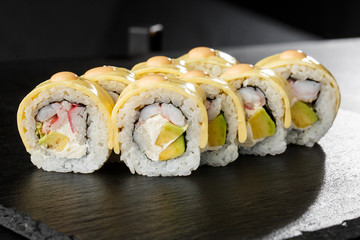 Sushi Rolls with processed cheese, cheddar, american cheese, avocado, crab meat, shrimp and Cream Cheese inside on black slate isolated. Philadelphia roll sushi with shrimp. Sushi menu. Horizontal.