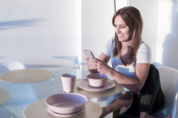 Attractive adult woman sitting at living room while using mobile phone