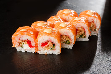 Sushi Rolls with flying fish caviar , fried onion, salmon and Cream Cheese inside and on black slate isolated. Philadelphia roll sushi with shrimp. Sushi menu. Horizontal photo.