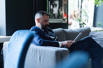 Handsome young man working with laptop while sitting on the couch in office