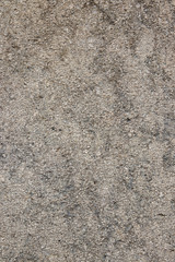 Gray texture of a concrete wall. Closeup of a gray brown of a weathered concrete wall with a hilly uneven surface with small stones. Abstract background concept.