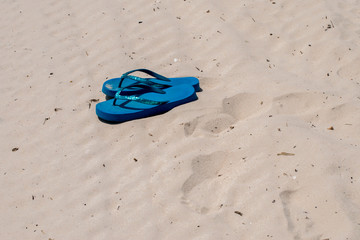 A pair of blue flip flops have been abandoned on the sandy beach in Mississippi on a hot summer...