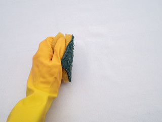 Hands wearing bright yellow rubber gloves on a white cloth background
