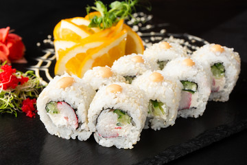 Sushi Rolls with avocado , cucumber, green onion and carrot inside on black slate isolated. Vegan california rolls covered white sesame seeds. Sushi menu. Horizontal photo.
