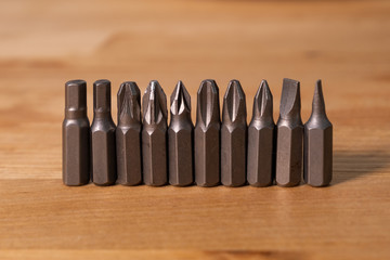 Various screwdriver heads in a horizontal row on a natural solid wood table. Close up.