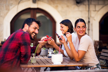 Group of people using phones while sitting in a cafe bar