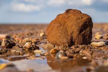 A large stone surrounded by smaller stones in Snettisham Beach, Norfolk, England, UK