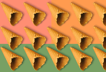 Waffle cones for ice cream on an orange, green and pink background with copy space for insertion or decoration of text, logo or wording, concept of colorful summer cold sweet snacks. Pattern.