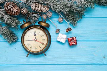 Christmas wooden background with snow fir tree, alarm clock and gift boxes.