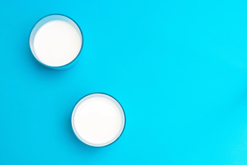 Two glasses of ayran (kefir) yogurt-based beverage with salt and water on blue background.