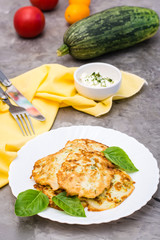 Vegetable fried fritters from zucchini and basil leaves on a plate on the table