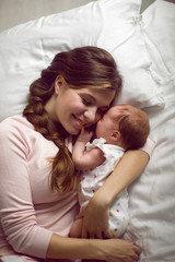mom with a small newborn daughter lying on the bed