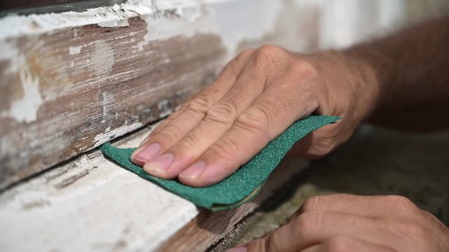 Slow motion shot of a man's hand sanding a worn window sill