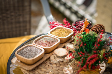 Spices in wooden bowls with autumn decorations on the wooden table