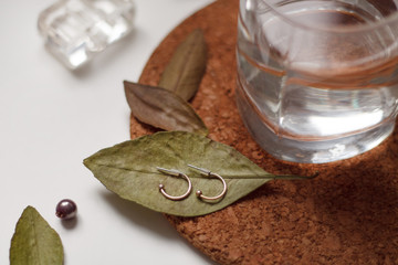 earrings women's jewelry lie on a green leaf close up on a stand cork and a glass of water on a light background