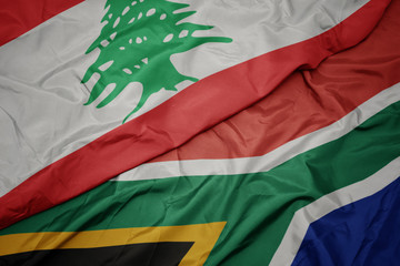 waving colorful flag of south africa and national flag of lebanon.