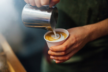 Barista making coffee in coffee shop, hands holding cup of coffee.