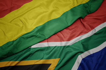 waving colorful flag of south africa and national flag of bolivia.