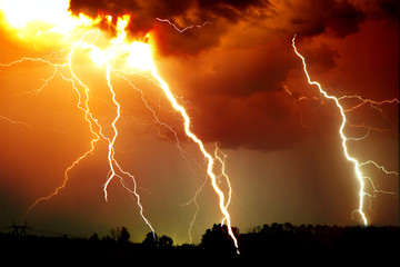 Lightning strike on the dark cloudy sky. Orange, yellow and red toned image - 300428443
