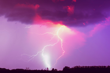 Naklejka na ściany i meble A lightning strike on the cloudy sky. Pink, lilac and purple toned image