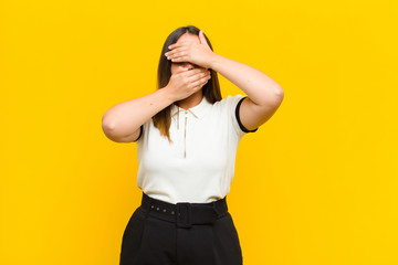 young pretty woman covering face with both hands saying no to the camera! refusing pictures or...
