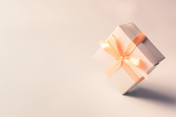 Gift box with beige ribbon on a white background, isolate. zero gravity. levitation. Copyspace. The...