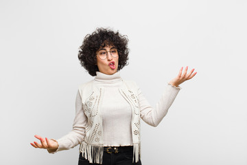 young pretty afro woman shrugging with a dumb, crazy, confused, puzzled expression, feeling annoyed...