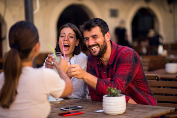 Smiling friends talking at terrace in a cafe bar