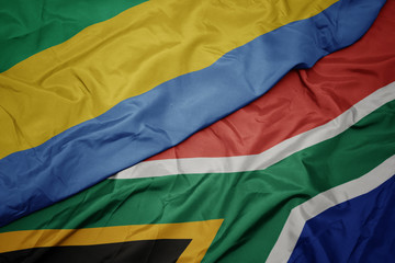 waving colorful flag of south africa and national flag of gabon.