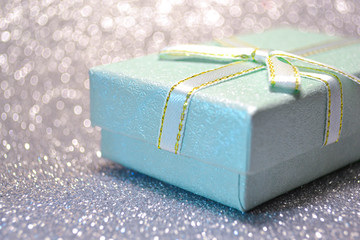 Decorative trendy green mint gift box with a little turquoise and gold bow standing in a sparkle...