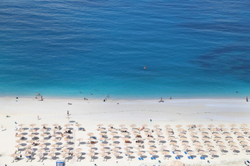 Crowded beach with sunshades, blue ocean