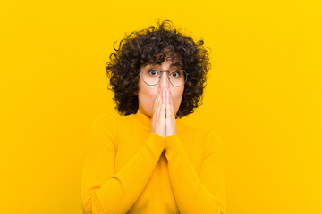young pretty afro woman feeling worried, upset and scared, covering mouth with hands, looking...